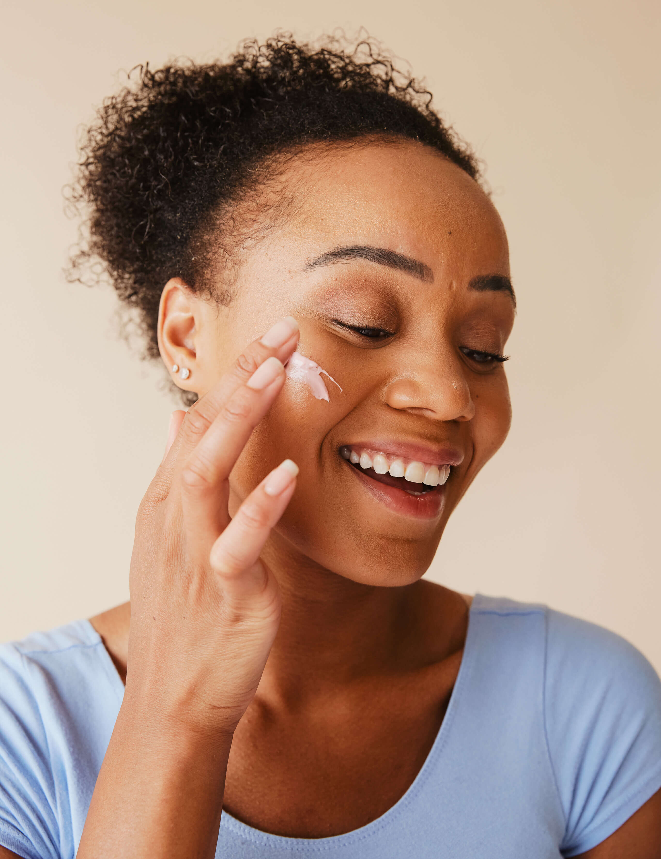 Smiling woman applying Raw Organic Cosmetics organic retinol face cream, highlighting its hydrating and anti-aging benefits for radiant, youthful skin.