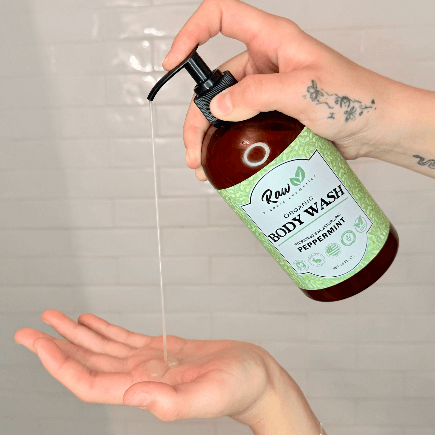 A woman pouring organic peppermint body wash into her hands in the shower. Made with natural, hydrating ingredients like organic peppermint and shea butter, this body wash offers a refreshing, gentle cleanse that's perfect for sensitive skin.